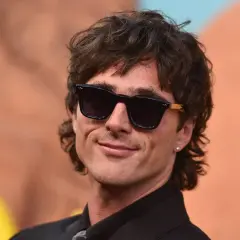Hombre con corte de pelo moderno, gafas de sol oscuras y sonrisa. Un estilo que anticipa el corte de pelo hombre 2026.