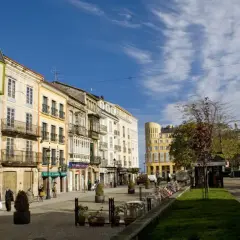 Paseo por el casco antiguo de Ribadeo que ver: fachadas coloridas, balcones de hierro y un cielo azul con nubes.