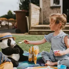 Dziewczynka karmi pluszową pandę na pikniku. Wspaniałe zabawy dla 5-6 latków w domu i ogrodzie.