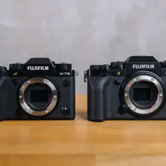 Dwa aparaty Fujifilm: X-T5 i X-T4, stojące obok siebie na drewnianym stole.