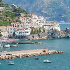 Amalfi: cosa vedere in un giorno. La pittoresca cittadina si affaccia sul mare blu, con case bianche aggrappate alla collina e un porto pieno di barche.