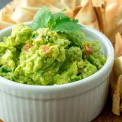 Pyszne guacamole z pomidorami i kolendrą, idealne do szybkiego przygotowania. Podane z chrupiącymi nachos.