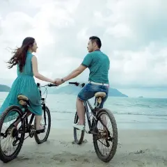Para jak przeprosić, trzymając się za ręce na rowerach na plaży.