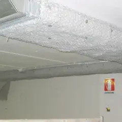 Condotti metallici coperti da rete e materiale isolante, con segnale di estintore. La pittura ignifuga protegge le strutture.