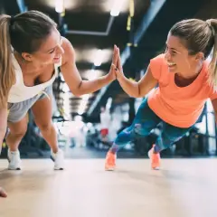 Dwie uśmiechnięte kobiety robią pompki w siłowni, świętując sukces. Chcesz wiedzieć, jak zdobyć kartę Multisport?