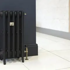 Stary, czarny grzejnik żeliwny z mosiężnymi zaworami. Woda w grzejniku żeliwnym jest kluczowa dla jego działania.