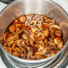 Gotowanie suszonych grzybów do pierogów. W garnku na kuchence bulgoczą grzyby w aromatycznym wywarze.