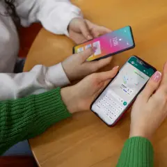 Dwie osoby korzystają z telefonów. Jedna z nich ma na ekranie mapę i klawiaturę, jak w systemie android 10.