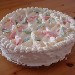 En vit gräddtårta dekorerad med rosa, gröna och vita Ahlgrens bilar. Perfekt för en festlig stund!