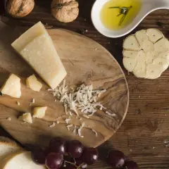 Kawałek sera romano, świeży chleb, winogrona, orzechy i oliwa z oliwek tworzą apetyczną kompozycję.