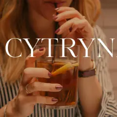 Kobieta pije herbatę z cytryną. Czy herbata z cytryną jest szkodliwa? Napój w szklance z lodem i plasterkiem cytryny.