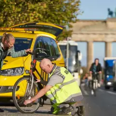 ADAC-Mitarbeiter hilft Frau bei einer **ADAC Fahrradpanne** vor dem Brandenburger Tor.