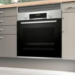Moderno horno integrado en una cocina con cajones grises y encimera de madera.