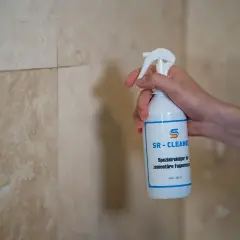 Hand hält SR-CLEANER Flasche, um **Fugen zu versiegeln** in der **Dusche**.