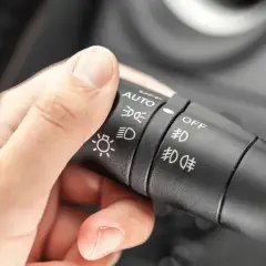 Dłoń kierowcy reguluje przełącznik świateł: auto, światła mijania, światła dzienne, przeciwmgielne.
