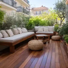 Terrasse en bois avec mobilier confortable, parfaite pour une rénovation extérieure maison. Plantes luxuriantes et vue sur les toits.