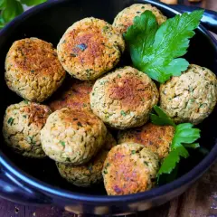 Köstliche Falafel, frisch zubereitet nach einem einfachen falafel rezept, liegen in einer schwarzen Schüssel, garniert mit Petersilie.