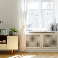 Elegancka osłona kaloryfera pod oknem, z ażurowym wzorem, stanowi stylowe rozwiązanie, jak zasłonić kaloryfer pod oknem, dodając wnętrzu uroku.