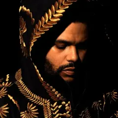 The Weeknd w czarnej, haftowanej złotem bluzie z kapturem, zamyślony. Jego utwory często opowiadają o mrocznych stronach życia.