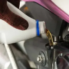 Rękawica nalewa nowy olej do silnika motocykla. Wymiana oleju w motocyklu to ważny krok w konserwacji.