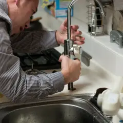 Un plombier ajuste un robinet, assurant la **durée garantie travaux plomberie**.