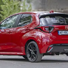 Czerwona Mazda 2 Hybrid widziana z tyłu, z czarnymi felgami i przyciemnianymi szybami.