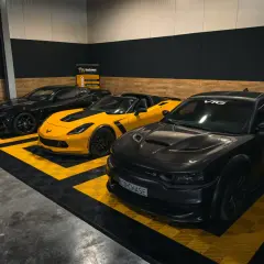 Trzy potężne amerykańskie marki samochodów: czarny Chevrolet Camaro, żółty Chevrolet Corvette i czarny Dodge Charger.