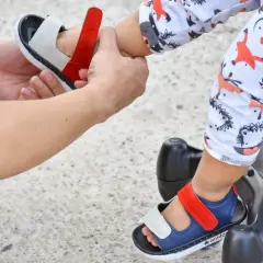 Dopasowywanie idealnych sandałów dla rocznego dziecka to wyzwanie. Na zdjęciu widać, jak rodzic zakłada dziecku wygodne sandałki.