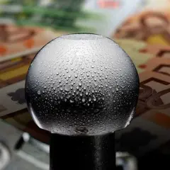Gocce d'acqua su un gancio traino, con banconote in euro sullo sfondo. Quanto costa omologare un gancio traino?