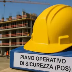 Elmetto giallo su un faldone con scritto "PIANO OPERATIVO DI SICUREZZA (POS)" in un cantiere edile in costruzione.