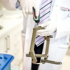 Lekarz w białym kitlu i rękawiczkach używa wiertarki do precyzyjnego narzędzia. Profesor Ząbek gdzie przyjmuje?