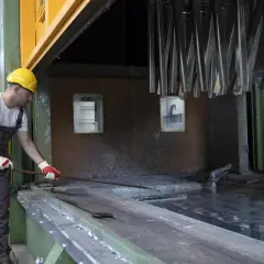 Pracownik w żółtym kasku i kombinezonie przygotowuje metal do malowania. Proces odtłuszczania metalu przed malowaniem domowe sposoby.