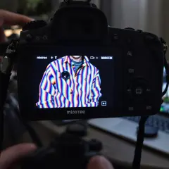 Na ekranie aparatu widać koszulę w tęczowe paski, na której widoczne są artefakty cyfrowe. To przykład, jak wygląda aliasing co to jest.