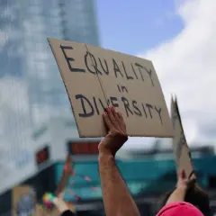 A hand holds a sign reading "EQUALITY in DIVERSITY," a powerful statement that inclusivity is a value.