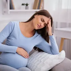 Kobieta w ciąży z bólem głowy, zastanawia się, kiedy niskie ciśnienie w ciąży wymaga wizyty w szpitalu.