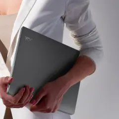 Kobieta w białej marynarce trzyma laptopa Lenovo Yoga. Czas na aktualizację systemu, by praca była płynna.