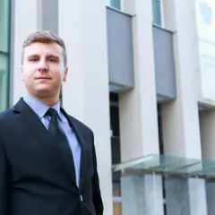 Mężczyzna w garniturze przed budynkiem sądu.