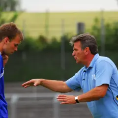 Trainer Martin Hoffmann gibt einem Spieler Anweisungen auf dem Fußballplatz.