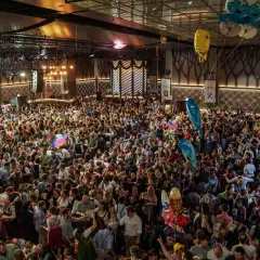 Volles Festzelt am Nockherberg 2026 mit vielen Menschen in Tracht, die Bierkrüge schwenken. Luftballons steigen auf.