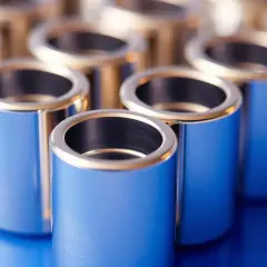 Błyszczące, metalowe tulejki w odcieniach niebieskiego i złota ustawione w rzędach na niebieskim tle.