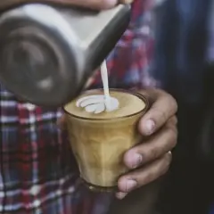 Barista wylewa mleko z dzbanka, tworząc wzór na kawie. To właśnie zabielacz do kawy, który nadaje jej kremową konsystencję i piękny wygląd.
