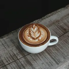 Eine Tasse Cappuccino mit Latte Art auf einem Holztisch. Die Menge des Kaffees ist perfekt für einen Genussmoment.