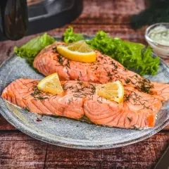 Zwei saftige Lachsfilets, perfekt im Airfryer zubereitet, garniert mit Zitrone und Dill. Dazu knackiger Salat und eine cremige Sauce.
