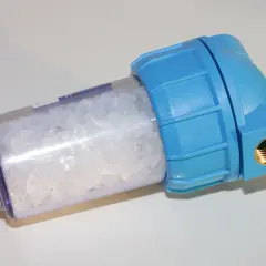 Filtre adoucisseur d'eau bleu rempli de cristaux blancs. Peut être la cause d'un problème de pression d'eau.
