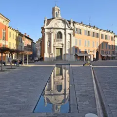 Piazza con chiesa barocca e specchio d'acqua, ideale per scoprire cosa vedere a Reggio Emilia in un giorno.