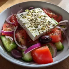 En fräsch grekisk sallad med fetaost, tomater, gurka, rödlök och oliver, toppad med örter.