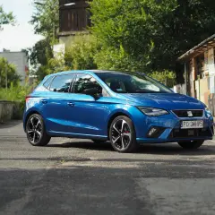 Niebieski Seat Ibiza na tle zieleni i budynków. Poznaj jego seat ibiza dane techniczne.