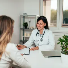 Sage-femme souriante discutant avec une patiente, évoquant une possible rééducation périnée.