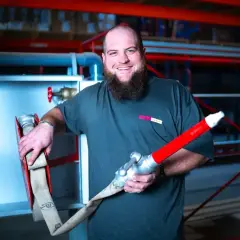 Mann mit Bart hält Feuerwehrschlauch und Düse bereit für die Wandhydranten Wartung.