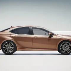 Elegancka, brązowa Toyota Camry używana, prezentująca swój dynamiczny profil na jasnym tle.